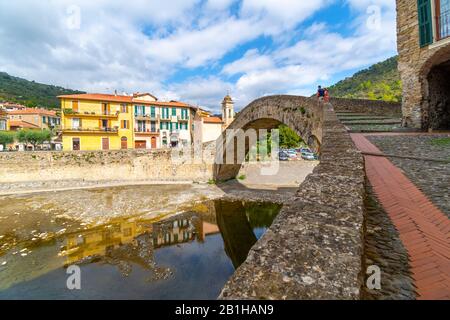 Una giovane coppia turistica si trova vicino al ponte ad arco Monet nel borgo medievale di Dolceacqua, Italia. Foto Stock