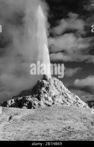 Geyser che eruttano e sparano un getto d'acqua nel cielo scuro. Foto Stock