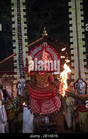 Theyyam interprete, come dio vivente, danze una forma rituale popolare di culto nel Kerala del Nord, vicino a Kannur, India. Foto Stock