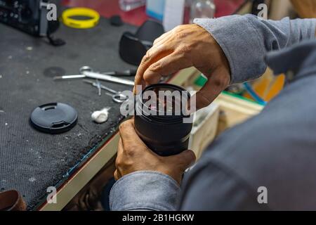Fotografia di primo piano del tecnico con lente della fotocamera amputata per la pulizia delle dita Foto Stock