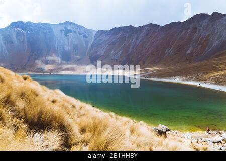 Un lago con acque cristalline, circondato da montagne innevate e un cielo blu con nuvole Foto Stock