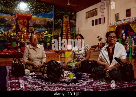 Tre donne sedute all'interno del tempio durante la celebrazione per l'apertura del più grande Buddha in America Latina Foto Stock