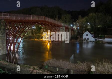 Ironbridge, Regno Unito. 26th Feb 2020. 2-3am al mattino, una settimana dal record precedente e Ironbridge sta ancora una volta sperimentando livelli di inondazione record. Mentre si trova all'ombra del famoso ponte, dopo il quale la città prende il nome, le difese delle inondazioni stanno battendo per tenere indietro i livelli del fiume in aumento, la lunga esposizione notturna crea una serena immagine millstagno del punto di riferimento storico stesso. Credito: Paul Bunch/Alamy Live News Foto Stock