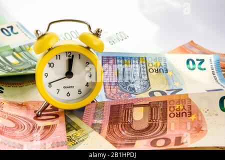 Sveglia con carta euro moneta 10, 20, 50, 100, sveglia su banconote, tempo è denaro Foto Stock