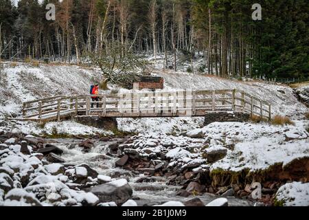 Un camminatore attraversa un ponte su un ruscello sul sentiero verso il monte Pen y Fan sul Brecon Beacons National Park, Galles, dopo che le temperature sono crollate durante la notte in Gran Bretagna, e i previsori hanno avvertito di più ghiaccio e neve nelle prossime 24 ore. Foto Stock