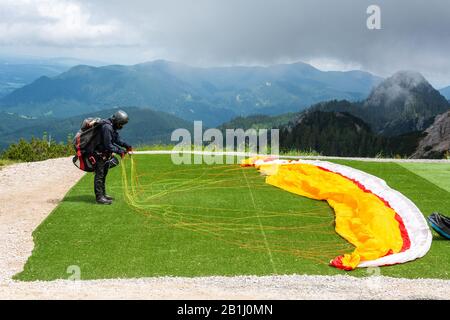 Un parapendio non identificato che prepara un lancio nella zona montagnosa vicino Fussen, Germania. Foto Stock