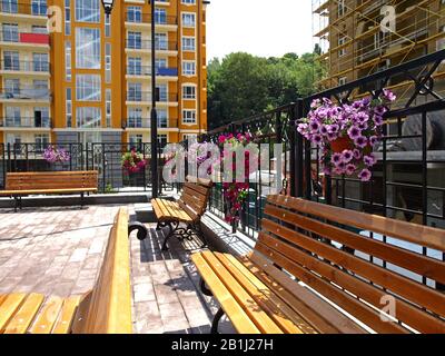 Kiev, Ucraina – 12 giugno 2018: Panchine con fiori nella zona di riposo superiore. Il nuovo quartiere colorato 'Vozdvizhenka' con nuove case Foto Stock