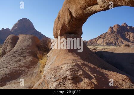 Pietra arenaria arco formazione di Spitzkoppe Erongo in Namibia con vista sulle montagne sullo sfondo Foto Stock