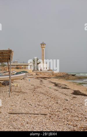 Imbarcazioni, moschea e minareto sulla spiaggia nel villaggio Pinne , Mar Arabico, Sultanato di Oman Foto Stock