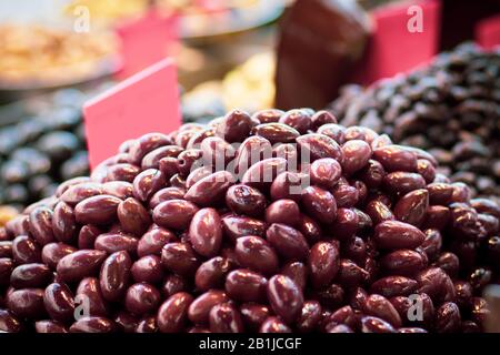 Un mucchio di olive marroni siriane lucide e piene di olio. Stile arabo. Il Vecchio Mercato Di Mahane Yehuda, Gerusalemme. Foto Stock