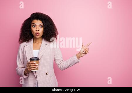 Ritratto di sorpresa afro americano ragazza tenere tazza bevanda indicare incredibile pubblicità promozione impressionato punto indice dito copyspace indossare a scacchi Foto Stock