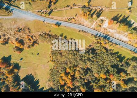 Vista dall'alto sul paesaggio autunnale. Foresta colorata, prato e autostrada Foto Stock