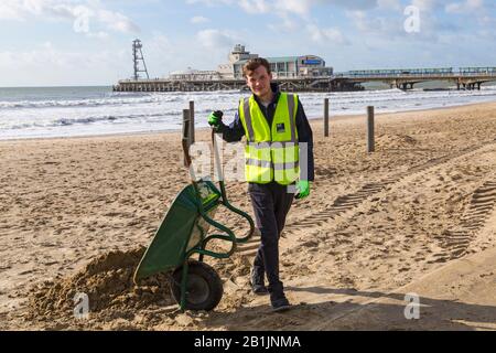 Bournemouth, Dorset, Regno Unito. 26th Feb 2020. Il consigliere Lewis Allison, si blocca e dà ai ranger del lungomare una mano per liberare la sabbia dal lungomare, soffiata dai recenti forti venti e Storm Dennis. L'Assessore Allison è Assessore al lavoro per Boscombe West e Titolare del portafoglio, membro del Gabinetto, per il Turismo, il tempo libero e le Comunità presso il Consiglio BCP (Bournemouth, Christchurch e Poole). Credit: Carolyn Jenkins/Alamy Live News Foto Stock