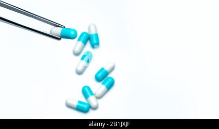 Forcipe prelevare la capsula bianco-blu dal gruppo di pillole. Farmaci scegliere. Selezione di farmaci antibiotici. Concetto di resistenza ai farmaci antibiotici. QA e QC Foto Stock