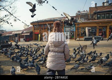 Il bambino guarda gli uccelli sulla piazza principale di Sarajevo, Bosnia-Erzegovina Foto Stock