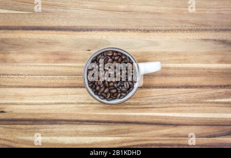 Vista dall'alto di un tazza bianca Riempita alla parte superiore con chicchi di caffè Organici Foto Stock