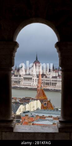 Palazzo del Parlamento ungherese visto attraverso una galleria di pescatori bastione sulla collina del Castello di Buda, Budapest con Foto Stock