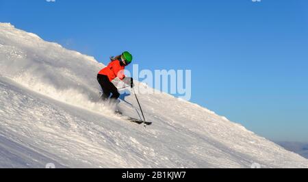 Sciatore femmina scendendo ripida pendenza pendenza nero, montagne dietro, SkiWelt Wilder Kaiser, Brixen im Thale, Tirolo, Austria Foto Stock