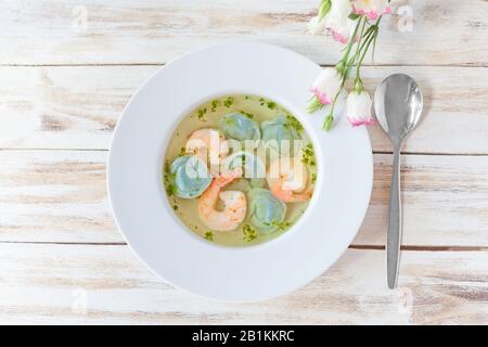 Gnocchi di zuppa e gamberetti serviti con porri. Su vecchio sfondo bianco di legno. Foto Stock