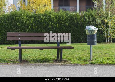 panca al parco pubblico con cestino rifiuti Foto Stock