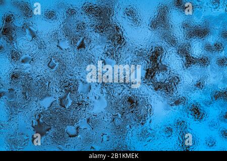 Astratto sfondo blu con gocce di pioggia sul vetro Foto Stock
