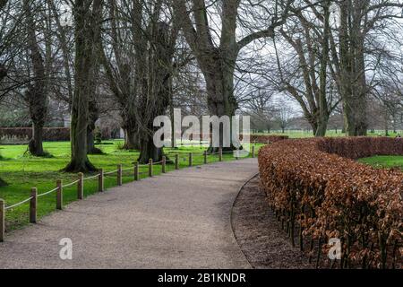 Scena invernale nei giardini di Castle Ashby House, Northamptonshire, Regno Unito; percorso di ghiaia curva tra alberi e siepi Foto Stock