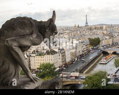 Vista del paesaggio urbano di Parigi, tra cui la Torre Eiffel e il fiume Senna, da una delle torri di Notre-Dame, con un Gargoyle in primo piano Foto Stock