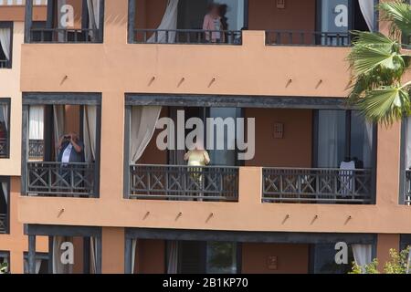 Tenero, Spagna. 26th Feb, 2020. Gli ospiti dell'hotel si trovano sui balconi dell'Hotel H10 Costa Adeje Palace a Tenerife. L'hotel di Tenerife, che è stato messo in quarantena a causa di casi di coronavirus, continua ad essere condonato dalla polizia. Credito: Arturo Rodríguez/dpa - solo per l'uso in conformità con accordo contrattuale/dpa/Alamy Live News Foto Stock