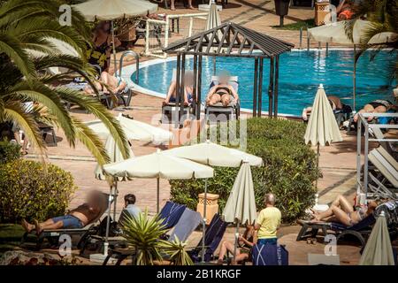 Tenero, Spagna. 26th Feb, 2020. Gli ospiti dell'hotel si crogiolano al sole presso la piscina. L'hotel di Tenerife, che è stato messo in quarantena a causa di casi di coronavirus, continua ad essere condonato dalla polizia. Credito: Arturo Rodríguez/dpa - solo per l'uso in conformità con accordo contrattuale/dpa/Alamy Live News Foto Stock