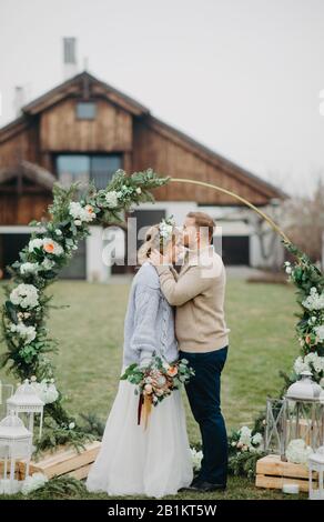Gli sposi si trovano vicino all'arco del matrimonio sullo sfondo del prato e della casa. Foto Stock