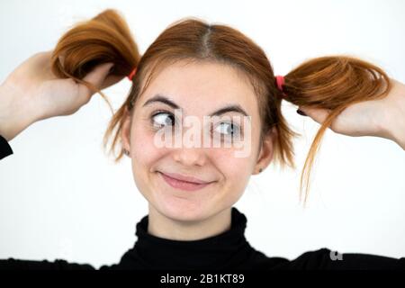 Closeup ritratto di un divertente redhead ragazza adolescente con infantile isolato di acconciatura su bianco backround. Foto Stock