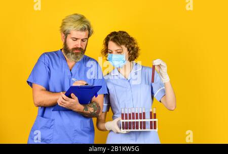 annotare le informazioni. dire no a coronavirus. rimedio antivirus in laboratorio. maschera respiratore medico. vaccino di infezione e analisi del sangue. Medico professionista di lavoro. Medico coppia uso di vaccinazione di tubo di prova. Foto Stock