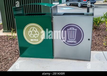 Due bidoni metallici per rifiuti in un parcheggio su una piazzola di cemento per materiali riciclabili e l'altra discarica insieme fuori primo piano Foto Stock