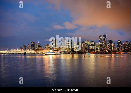 Vista degli edifici illuminati in città sulla costa dallo Stanley Park a Vancouver, Canada Foto Stock