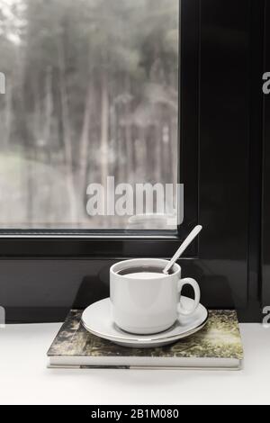 Una tazza di tè e un libro sul davanzale Foto Stock