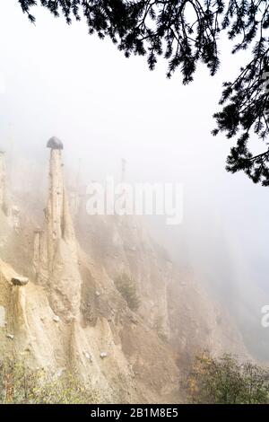 Cielo nebbioso in autunno sulle formazioni rocciose delle Piramidi della Terra, Perca/Percha, provincia di Bolzano, Alto Adige, Italia Foto Stock