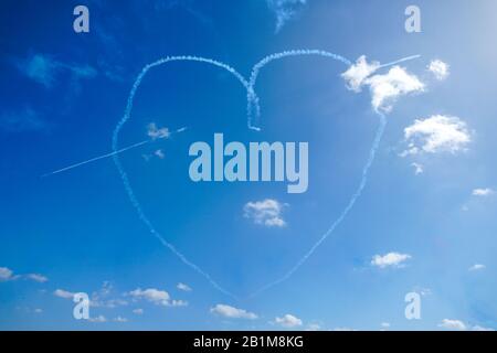 Piano che fa la formazione acrobatica e la creazione di una forma del cuore nel cielo blu. . Aeroplani su airshow Foto Stock