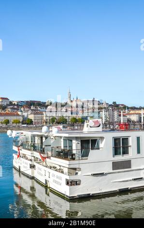 Budapest, Ungheria - 6 novembre 2019: Parte di un'enorme nave da crociera turistica sul Danubio nella capitale ungherese. Centro storico con il complesso del Castello di Buda e la Chiesa di Mattia sullo sfondo. Foto Stock