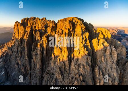 Veduta aerea del Sassolungo illuminata da una calda luce del tramonto autunnale, Val Gardena, Val di Fassa, Dolomiti, Alto Adige, Italia Foto Stock