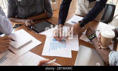 Le statistiche finanziarie della tabella closeup e le mani diverse di businesspeople che funzionano insieme Foto Stock