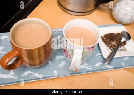 Due tazze di tè caldo con latte in attesa sul piano di lavoro Foto Stock