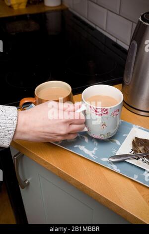 giovani donne che prendono la sua tazza di tè dal countertop Foto Stock