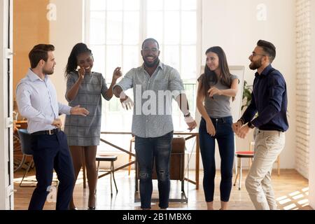 Attivo felice diversi uomini d'affari si sente felice ballare in ufficio Foto Stock