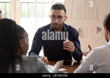 Diversi partner commerciali che ascoltano il leader del team arabo durante la riunione di gruppo Foto Stock