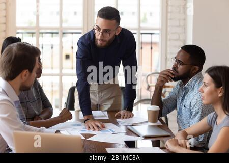Finanziatore dell'etnia mediorientale che presenta il rapporto di vendita per diversi colleghi Foto Stock