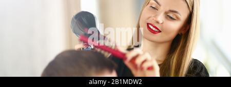 Ragazza giovane Parrucchiere Holding essiccatore e spazzola per capelli Foto Stock