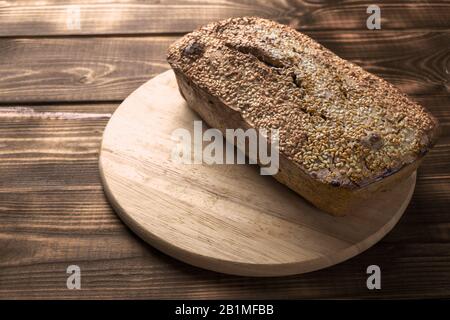 Pane di grano saraceno appena sfornato. Una pagnotta di pane si trova su una tavola rotonda da cucina su un tavolo di legno marrone. Prodotto domestico sano senza glutine. Naturale Foto Stock