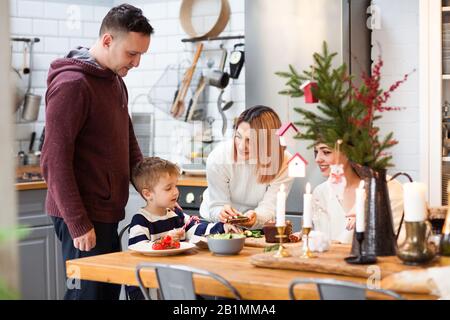 Famiglia con ragazzino a tavola che si gustano insieme le vacanze di Natale Foto Stock