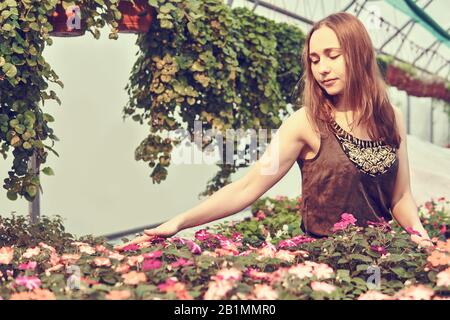 giovane donna in un abito con amore tocca i fiori in una serra Foto Stock