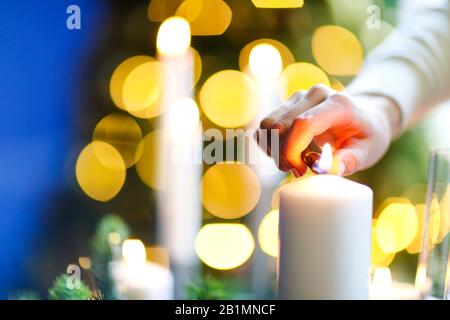 Donna irriconoscibile che sorride e accende le candele mentre crea un umore romantico in serata a casa Foto Stock